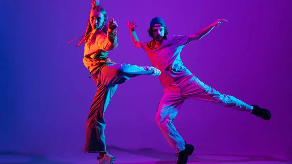 International Dance Day: Details Including Date, Historical Background, and Importance - Two dancers striking dynamic poses in colorful lighting.