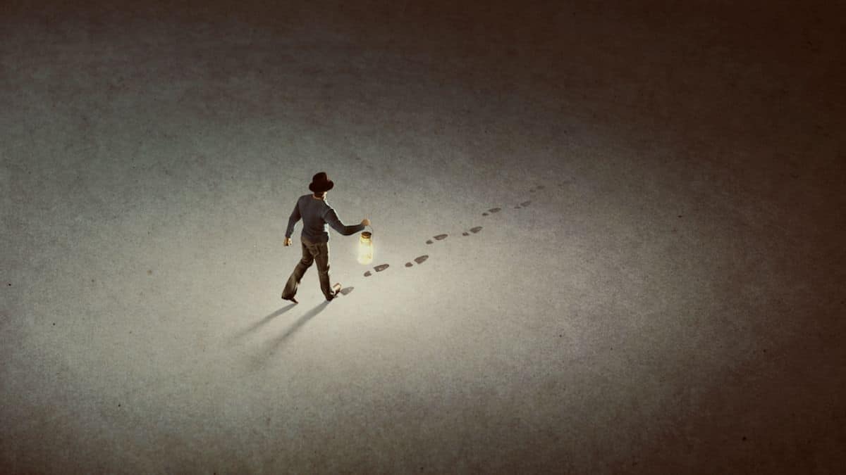 Man with lantern walking, leaving footprints in dim light.